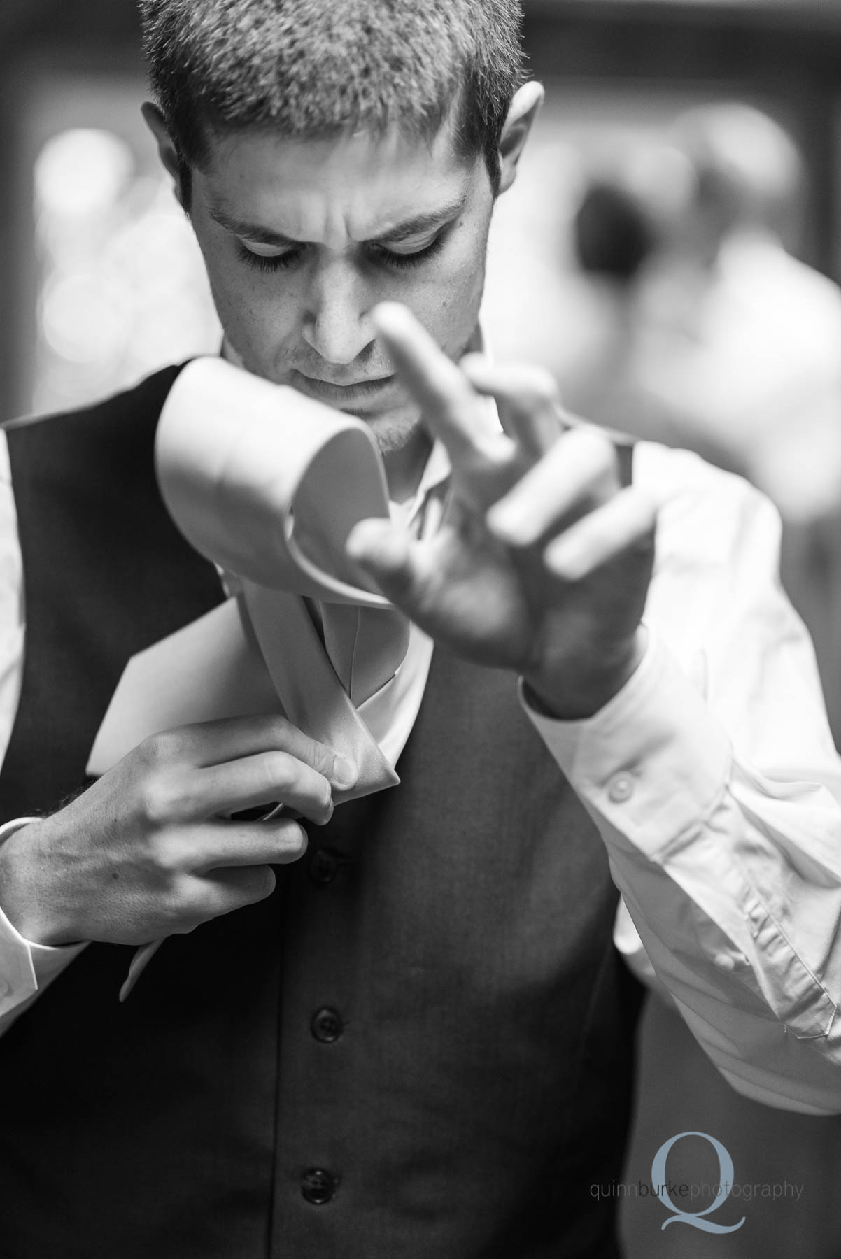 groom putting on tie for wedding