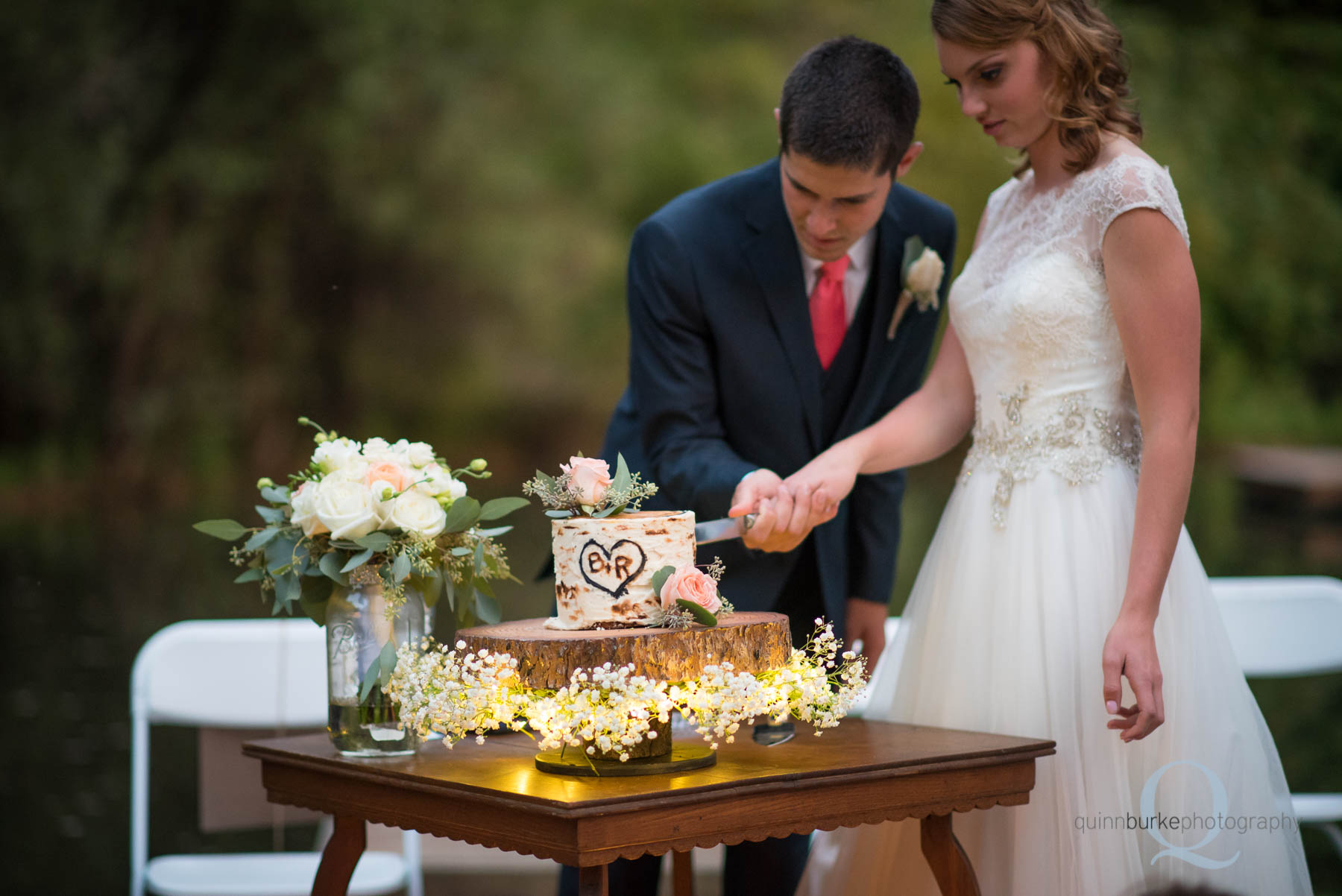 bride and groom cut the cake during reception at rons pond