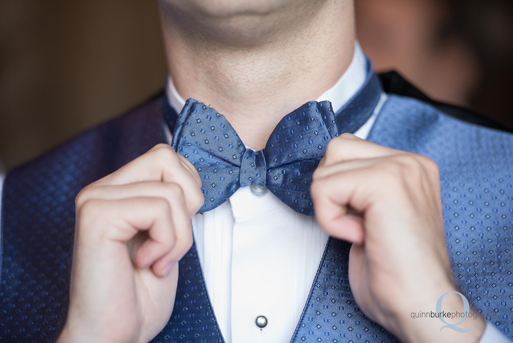 groom straightening bowtie for wedding