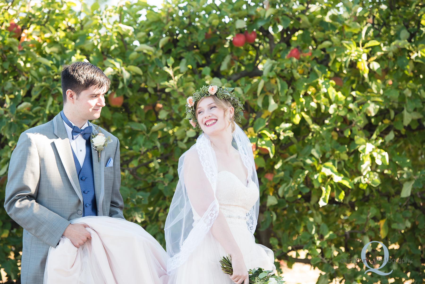 groom carrying bride dress train in orchard Perryhill Farm