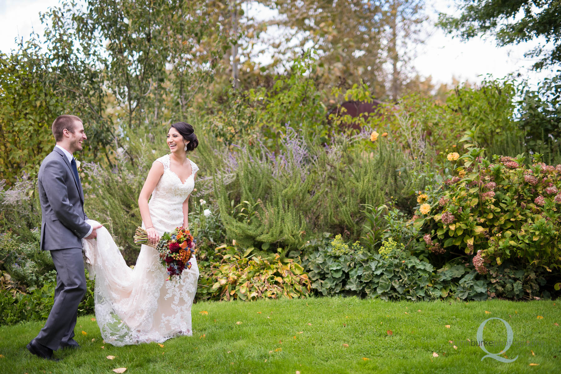 groom helping bride with dress in garden at Green Villa Barn